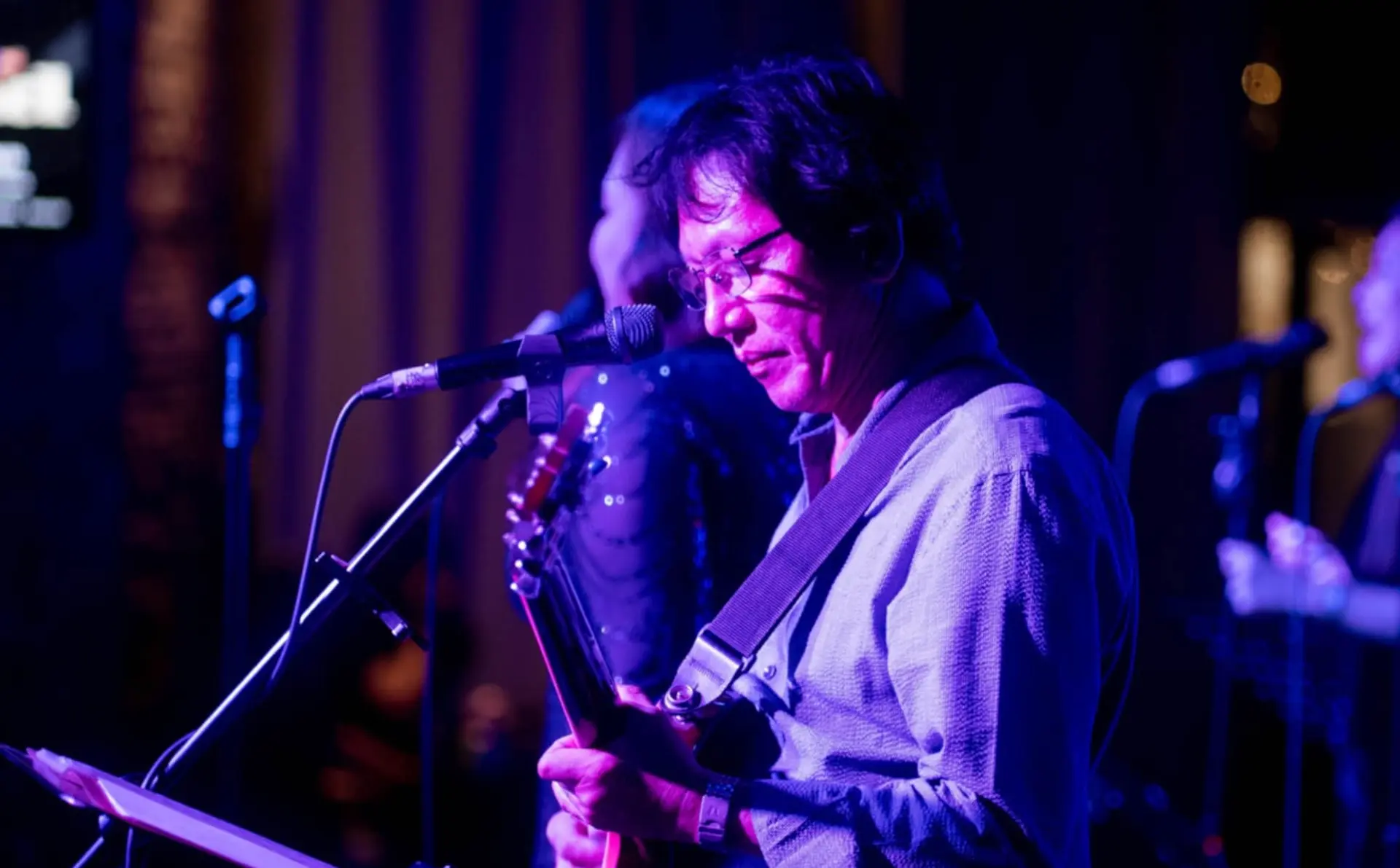 Resty Garcia singing and playing guitar under stage lighting during a live band performance